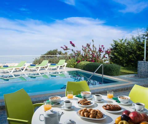 Danae Villas Hersonissos Crete Green Villa poolside table full of breakfast, pool and sunbeds