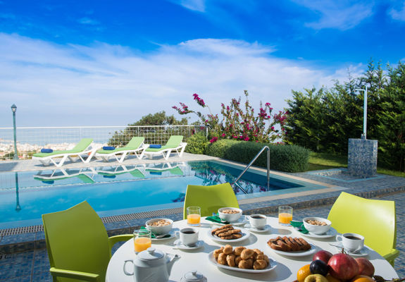 Danae Villas Hersonissos Crete Green Villa poolside table full of breakfast, pool and sunbeds