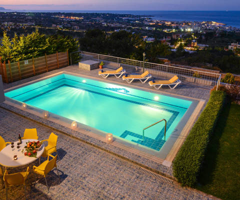 Danae Villas Hersonissos Crete Yellow Villa poolside table, sunbeds and pool at dusk